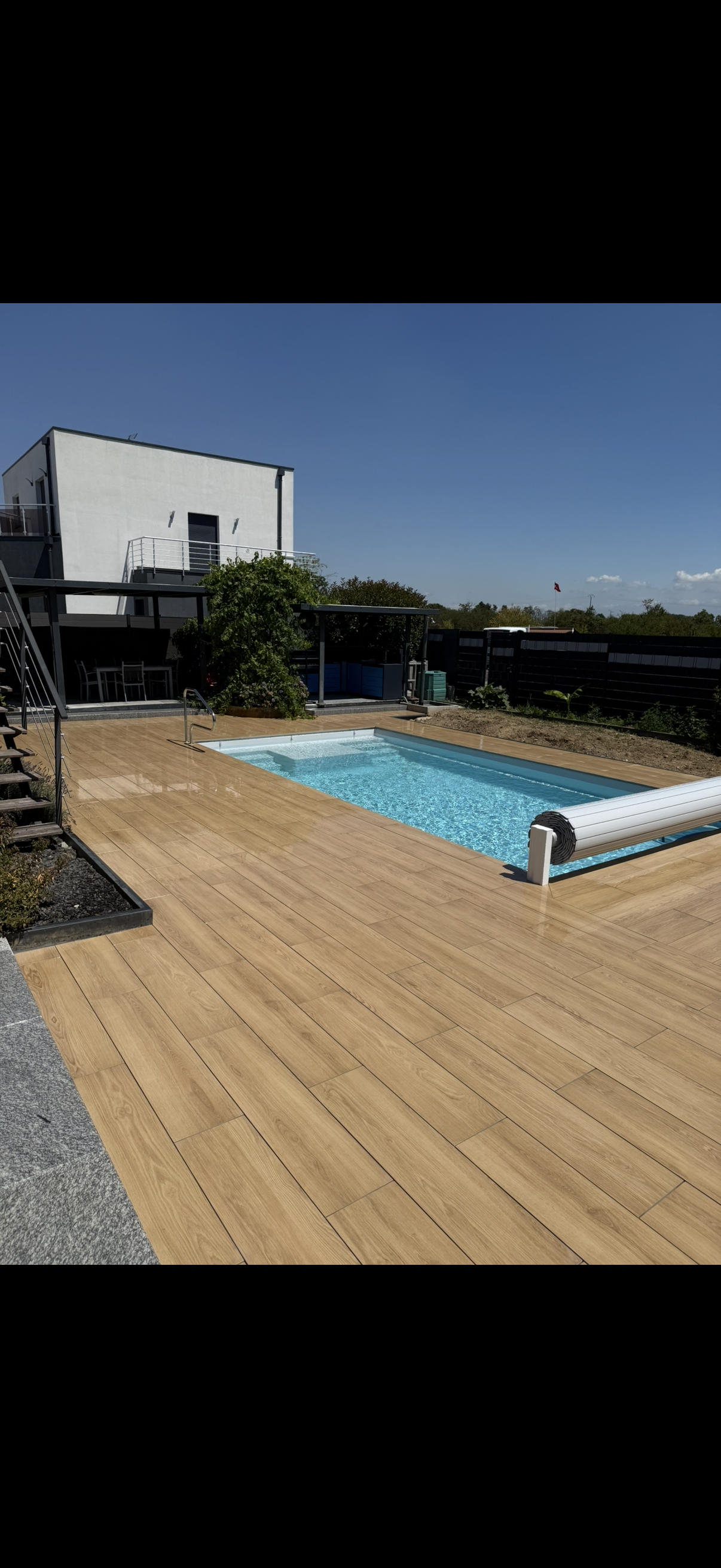 Piscine avec terrasse imitation bois vue large maison moderne