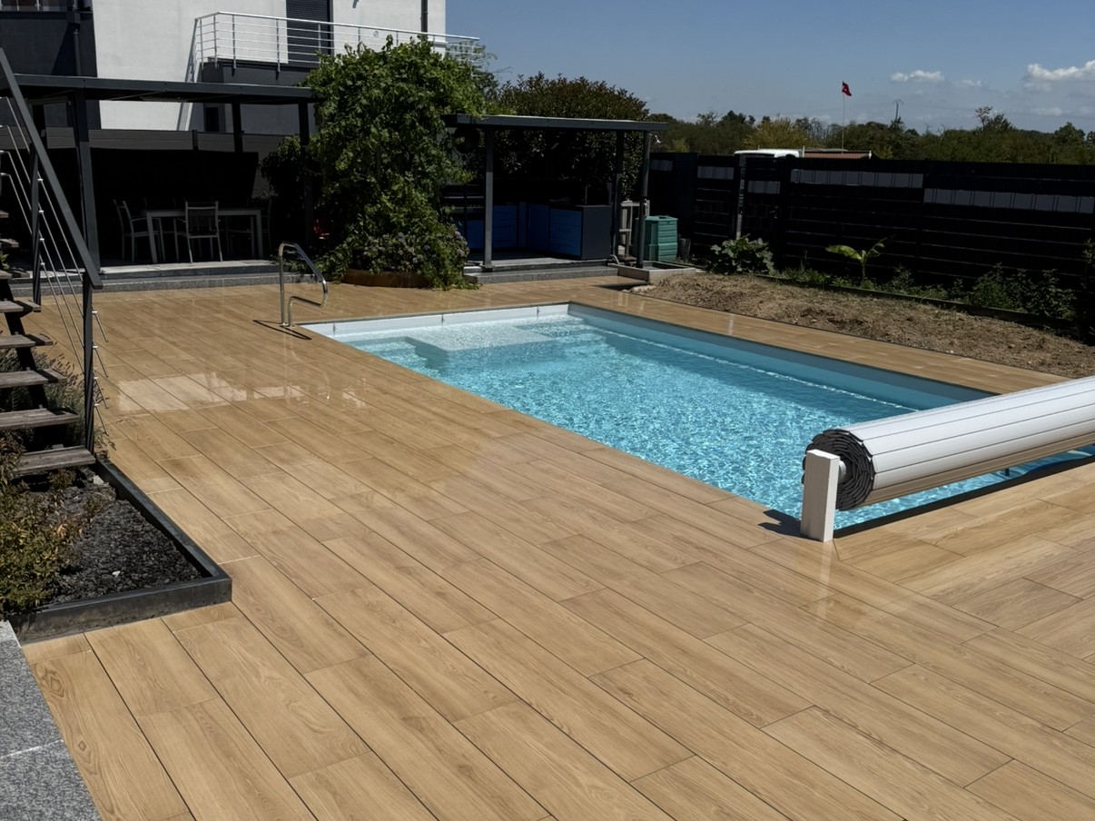 Piscine avec terrasse imitation bois et volet de sécurité par Infini Paysage